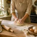 Woman kneading homemade bread dough on a wooden table in a warm, old-fashioned farmhouse kitchen.